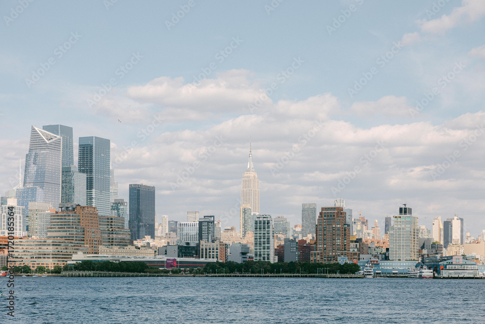 Fototapeta premium View of New York City skyline featuring modern buildings and the iconic Empire State Building on a clear day