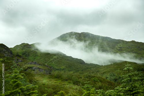 paisaje de montañas cubiertas de verde con niebla en la cima típico de paisajes de Escocia