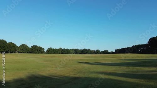 Low POV drone flyover of a grassy field in early morning light at Dix Park in Raleigh