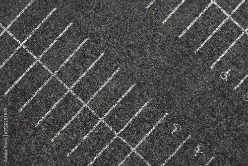 Aerial view of an empty parking lot with clearly marked spaces and road lines. The structured layout and asphalt surface highlight urban organization and infrastructure for vehicle parking and traffic