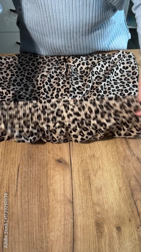 A woman unboxing and reviewing leopard print shorts. Vertical video