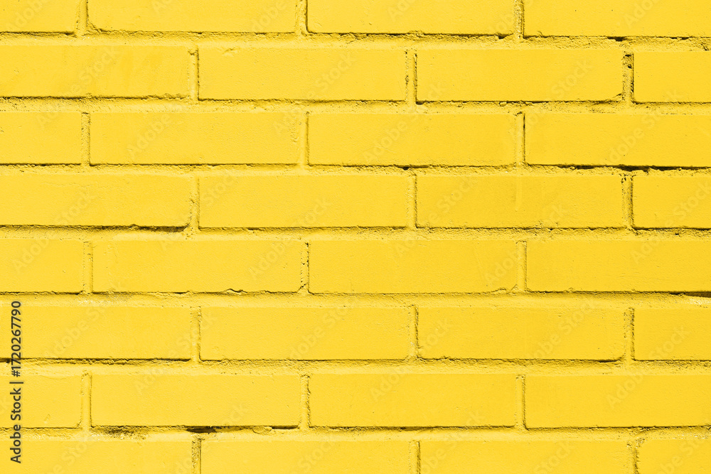 Obraz premium Yellow painted brick wall background. Urban surface with vibrant color. Industrial construction with texture and pattern. Simple geometry of rectangular bricks. Design element for architecture.