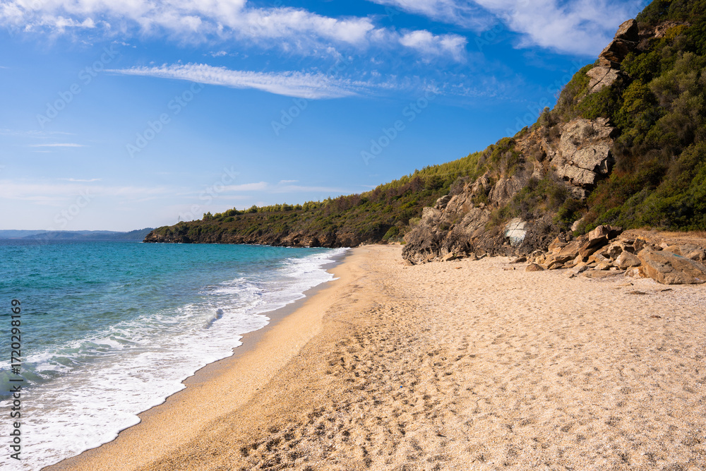 Obraz premium Sandy Irini beach in Greece with turquoise waters and rocky green hills.