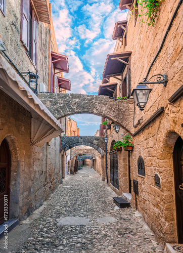 Narrow cobblestone alley with stone houses in the medieval old town of Rhodes, Dodecanese, Greece.