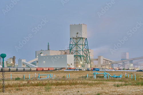 Industrial potash facility in Saskatchewan photographed at night with illuminated buildings and rail transport under a dark sky.