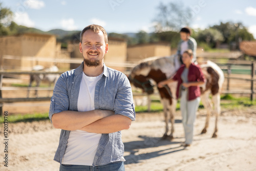 Photos Young man posing near paddock with boy riding horse