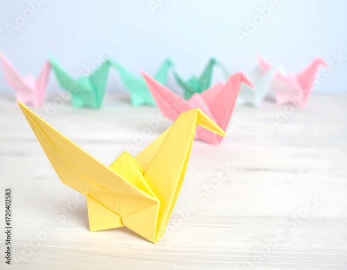 Pastel origami cranes on a light wood surface