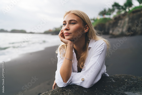 Woman looks into distance over ocean, reflecting inner harmony and the strength found in disconnecting from constant digital noise to embrace quiet mental clarity and natural focus.