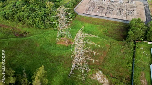 Aerial drone view of an electrical power substation surrounded by residential buildings and greenery.