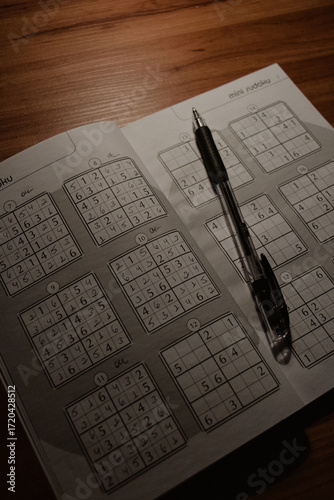 Sudoku Puzzle Book with Pen on Wooden Table