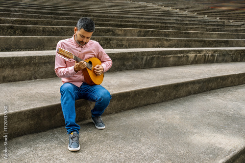 Man playing mandolin on concrete steps outdoors