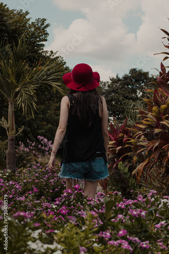 Woman in Red Hat Walking Through Flower Garden