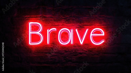 A neon sign displaying the word Brave glows brilliantly against a weathered brick wall, evoking a sense of courage and strength. The sign’s luminosity underscores resilience and valor. Stock Image.