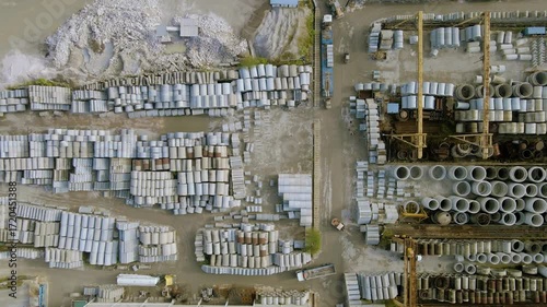 Aerial top view of a cement and concrete factory with rows of pipes, industrial storage, and solar panels on rooftops, showing large-scale construction material production site.