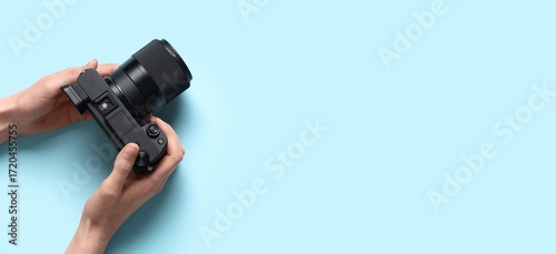 Cuadro en lienzo Hands holding modern professional photo camera on blue background with space for