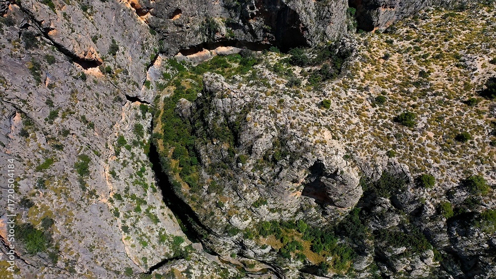 Obraz premium Aerial view of the narrow gorges and ravines created by the Amadorio River as it passes through the village of Relleu, Spain.