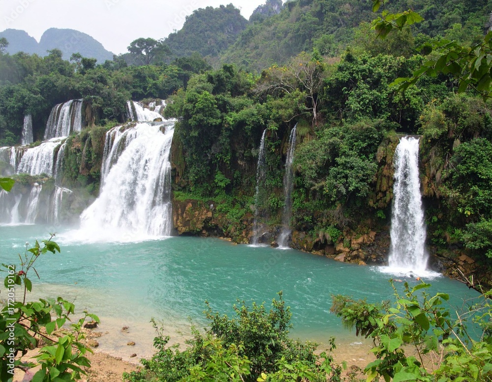 Fototapeta premium Ban Gioc waterfall in Vietnam, multiple cascading waterfalls dropping into turquoise river surrounded by lush tropical jungle and mountains, scenic travel destination and famous natural attraction in 