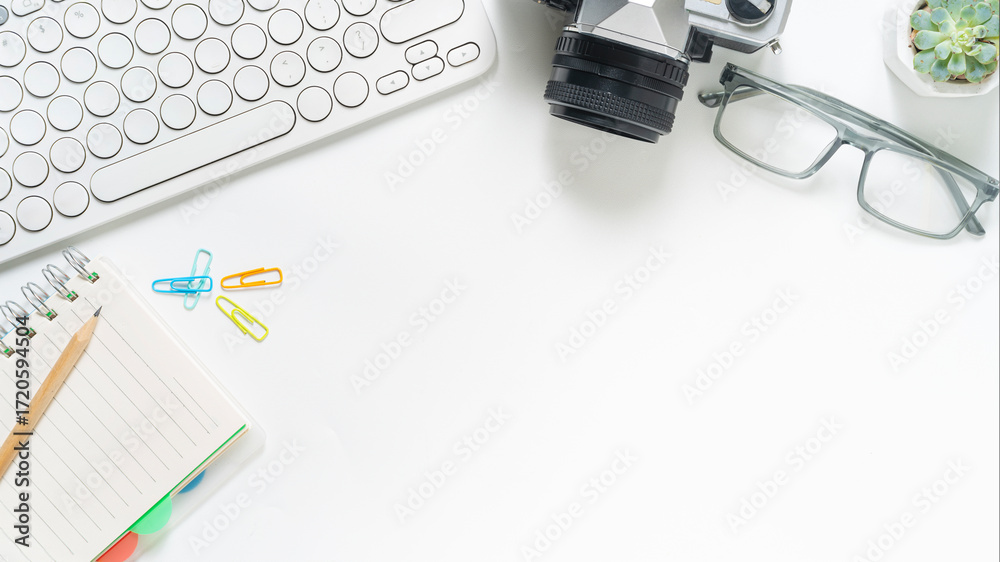 Fototapeta premium Clean white office desk flatlay with modern keyboard, vintage camera, eyeglasses and succulent for creative workspace and productivity vibes