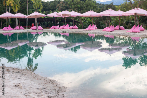 Pink umbrellas on the artificial sea behind are beautiful green mountains