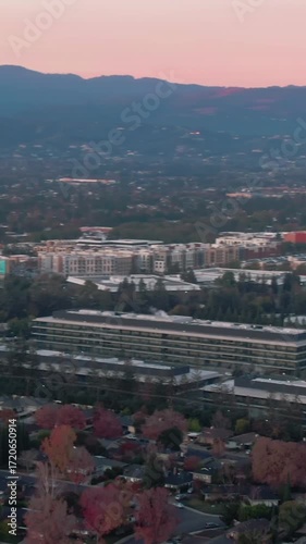 Aerial view of office buildings and residential homes in Cupertino, Silicon Valley, California, USA, at sunset. The image shows the blend of work and life in the tech hub.