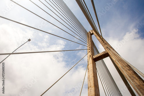 Architectural detail of the Mahkota II (Achmad Amins) Bridge in Samarinda, Indonesia. This dramatic low-angle shot highlights the grand concrete pylon and geometric pattern of a cable-stayed bridge