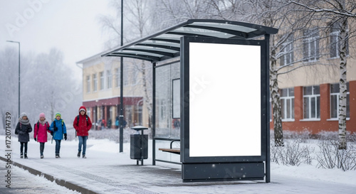 Children walking past winter bus stop with blank advertisement