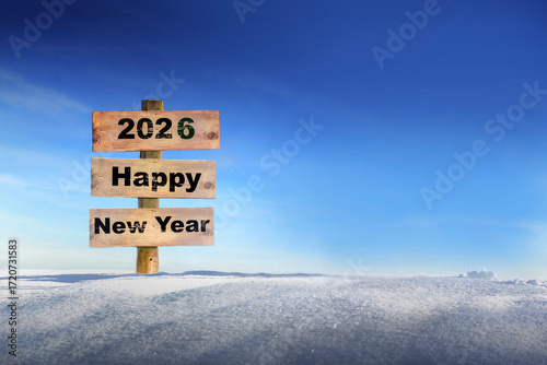 2026 HAPPY New Year written on a wooden sign planted in the snow against a bl...