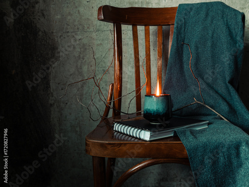 Rustic still life with candle, chair, notebook and fabric, cozy wabi sabi aesthetic, calm and mindful atmosphere.