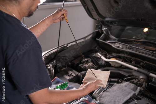 A man is wiping the oil dipstick to make sure it's ready.