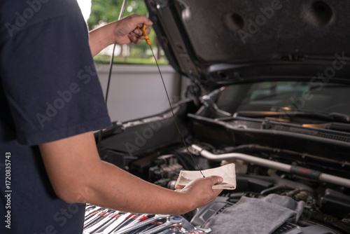 A man is wiping the oil dipstick to make sure it's ready.