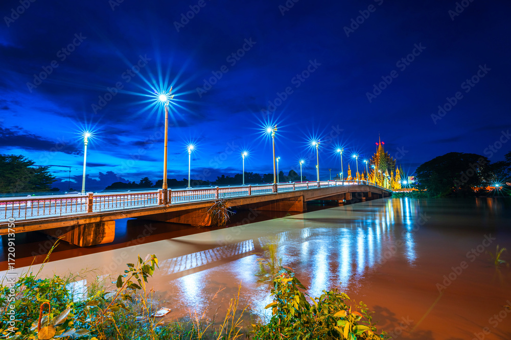 Fototapeta premium The color of Night traffic light on the road on the bridge (Suphankanlaya Bridge) It's a bridge across the Nan River at public in Phitsanulok city, Thailand at Twilight dramatic sunset sky background