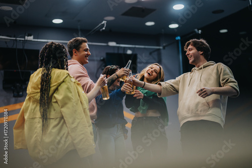 Fotografia Group of friends sharing joyful moments, raising bottles to toast while enjoying an uplifting time in a casual indoor setting