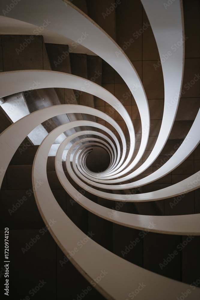 Fototapeta premium Top-down view into spiral staircase forming graphic vortex
