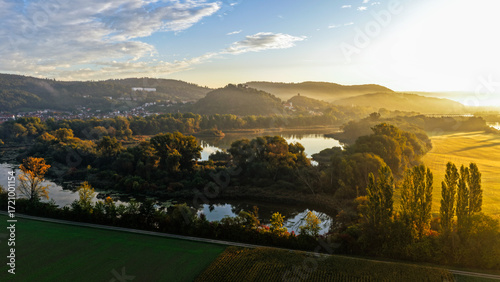 Sunlit River Bend Surrounded by Autumn Trees and Hillside Village