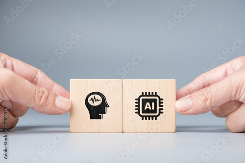 Close-up of two human hands holding wooden blocks with brain and AI chip icons symbolizing collaboration between human intelligence and artificial intelligence for innovation and creative application