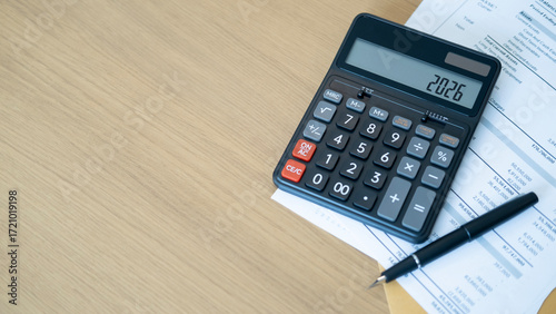 Bild auf Leinwand A black calculator displaying 2026 with a fountain pen and financial documents on a wooden desk