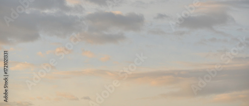 Multiple nuages dans un ciel rosé, bleu et gris au lever du soleil, format bannière