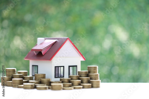 Mortgage,Model house and stack of coins money on natural green background,Business investment and real estate concept