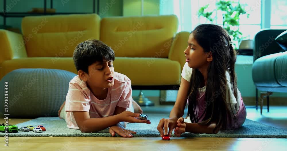 Small Sibling Indian Asian small sibling kids playing toy car race while lying on ...