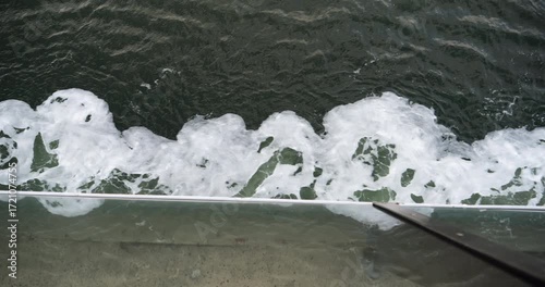Dynamic view from a large tanker showing white sea foam trailing over deep moving water captured in 4k dci motion as a real scene of ocean movement below deck