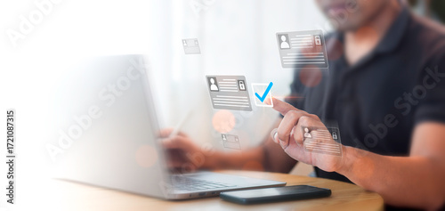 Person working on a laptop while checking digital identification cards at home during daytime