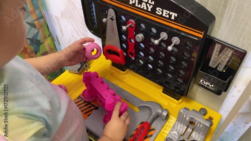 Little toddler child playing repairman mechanic with toy tools and fixing repair car