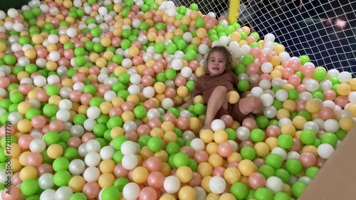 Little Girl Toddler Playing in Colorful Ball Pool in Children Playroom playground