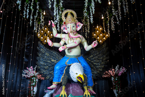Decorative idol of Lord Ganesha seated on Garuda with festive lighting and floral decor