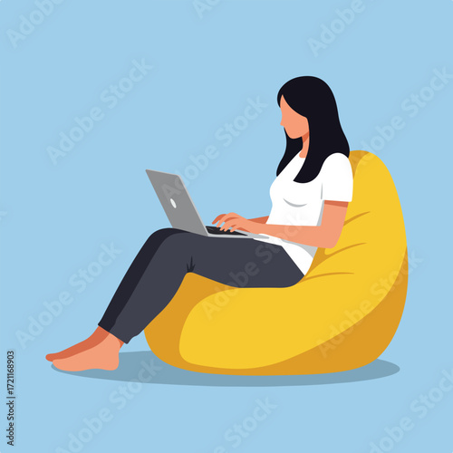 Woman sits, works at laptop on a beanbag chair