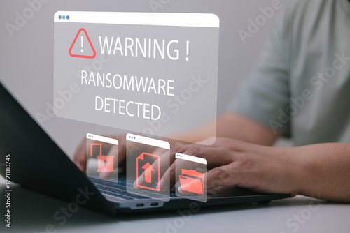 Proactive ransomware defense concept with warning message on screen, showing malware alert while hands type on laptop, related to cyberattack prevention, data protection, and network security system.