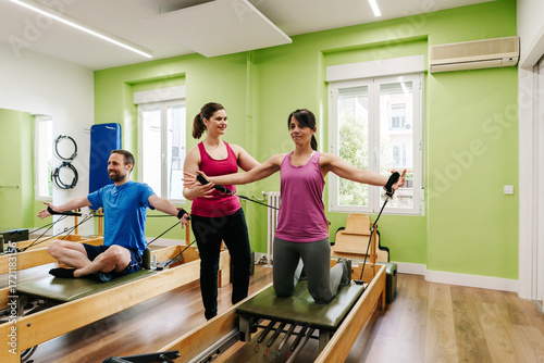 Pilates instructor guiding woman during reformer workout in fitness studio