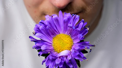 An allergy sufferer sniffs flowers against a black background.
Allergies to plants and flowers.
A purple aster in the hands of a florist.