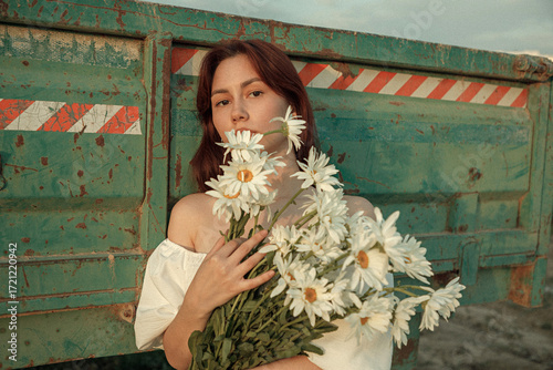 a young girl in a beautiful beige dress with flowers near the cart. film and grain effect