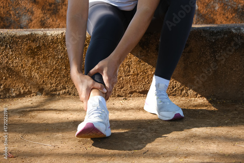 Young adult woman with muscle pain while running. A runner has a sore foot due to plantar fasciitis. Sports injury and medical concept